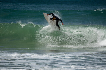 Wall Mural - male surfer catching waves surfing at south coast beach on a bright warm sunny day on clear blue water