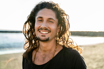 Portrait of happy handsome hippie italian man with long hair smiling beautiful to the camera. Wanderlust. Tropics. Traveler.Beach. Relax.