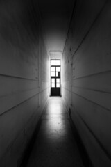Wall Mural - high dark spooky corridor with light at the end and high doors.