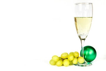 Glass of champagne next to bunch of grapes and Christmas decoration