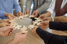 Hands Of Business People, Dressed In Casual Shirts, Hold A Paper Puzzle And Solve The Puzzle Together, Business Team Assembles The Puzzle, Business Team Wanting To Assemble The Puzzle Pieces.