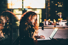 Woman Using Laptop On Night City Street.