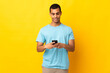 © luismolinero - African American man over isolated background sending a message with the mobile