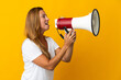 © luismolinero - Middle age brazilian woman isolated on yellow background shouting through a megaphone to announce something in lateral position