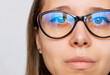 © Марина Демешко - Cropped shot of woman's face with red and black female glasses for working at a computer with a blue filter lenses isolated on a white background. Anti blue light and rays. Eye protection. Close-up