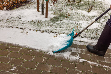 Closeup view of a person clearing snow on alley with a shovel. Winter season concept background.