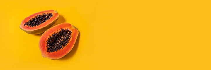 Fresh two halves of papaya on yellow background, top view. Banner. Space for text