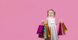 © галина шарапова - Cute little girl in a party dress on pink background holding colorful bags