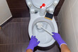 Man hand cleaning toilet with brush, toilet is thoroughly cleaned with a brush