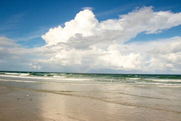 A Rainbow over the ocean, seen from the beach. 