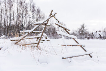 Haystack wooden frame on the field in snowy winter day