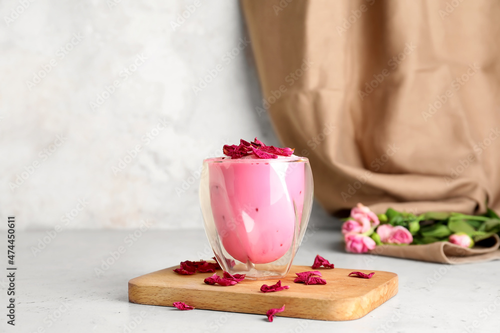 Glass of tasty rose latte on light background