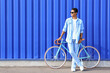 © Pixel-Shot - African-American teenage boy in sunglasses with bicycle near blue fence