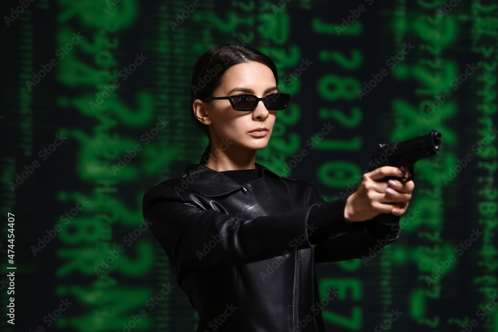 Woman with gun dressed in matrix style on dark background