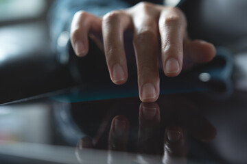 Close up of woman hand holding digital tablet pc and finger touching or pointing on touch screen with reflection, business and technology concept