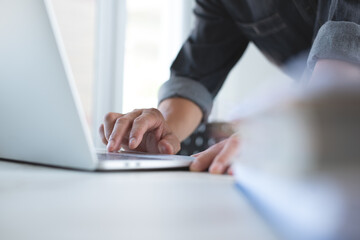 Close-up of man hands tying on laptop computer keyboard, busy working at modern office. Casual business man online working from home, telecommuting oncept