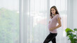 © SKW - portraits of new moms european woman Russia is pregnant standing beside the window holding his belly and smiling happily in the bedroom wearing a pink shirt and black pants