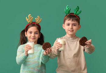 Poster - Funny little children with reindeer horns, milk and cookies on color background