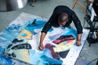 © zzzdim - Busy black man drawing lines on a big canvas with painting on a table