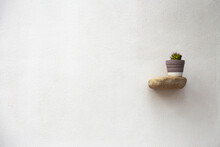 A Stone Shelf Is Fixed On A Flat White Wall, On Which There Is A Flower Pot With A Cactus