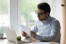 Serious 35s Businessman Holds Document Sheet, Read Post Paper Letter, Sorting Out Correspondence Sit At Workplace Desk In Office, Entrepreneur Learns Commercial Offer, Read Bank Notice, News Concept