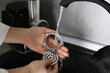© New Africa - Woman washing parts of electric meat grinder under tap water in kitchen sink indoors, closeup