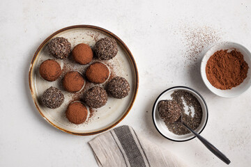 Wall Mural - Chia seeds cacao bliss balls on ceramic plate. Vegan protein energy balls. White background. top view