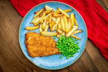 
Traditional English Homemade Fish And Chips With Peas On A Turquoise Plate With A Red Cloth.