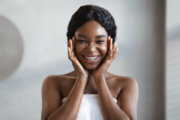 Wall Mural - Happy young black lady applying eye care product