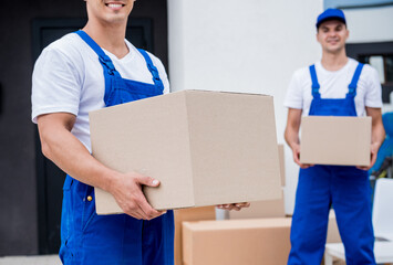 Two removal company workers are loading boxes into a minibus.