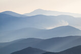 Fototapeta Natura - Blue silhouette of mountains on horizon, early misty morning.