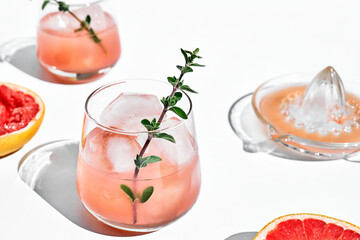 Wall Mural - Summer grapefruit cocktail. Fresh healthy grapefruit beverage with herbs on sunlight with hard shadows. Creative drink with palm leaf on light blue pastel background.