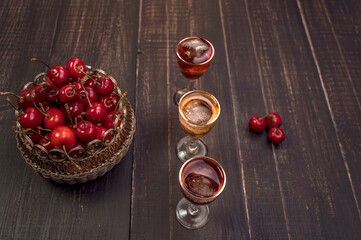 Alcoholic drinks in glass piles on a wooden table. Cherry, nut and lemon liqueurs.