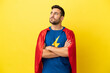 © luismolinero - Young handsome caucasian man isolated on yellow background in superhero costume with arms crossed