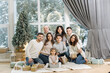 © Aleksandr - Portrait of noel large family gathering. One big stylish family. Grey-haired grandparents, granddaughter, grandson, brothers, sisters, grandchildren sitting on floor, getting gifts. Fir tree