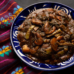 Wall Mural - Mexican romeritos with mole sauce and shrimp on a dark background