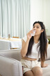 © Piyadanai - portrait of beautiful woman drinking water,sitting on sofa at home