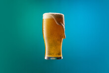 Full Glass Of Frothy Light Lager Beer Isolated Over Gradient Blue And Green Color Background In Neon. Concept Of Alcohol, Drinks And Festivals.