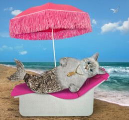 Wall Mural - An ashen cat mermaid with a silver fish tail lies on a sun lounger under a umbrella by the sea.