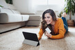 © Westend61 - Happy woman doing home shopping through credit card and tablet PC
