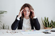 © Westend61 - Tired businesswoman with head in hands sitting at desk in office