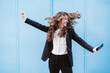 © Westend61 - Happy businesswoman dancing holding smart phone in front of blue wall
