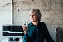 Senior Businesswoman Holding Drinking Glass In Office