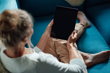 Woman using tablet PC on sofa at home