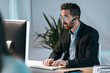 © Westend61 - Businessman wearing bluetooth working on computer at office