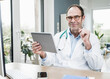 © Westend61 - Smiling doctor with tablet PC at desk in hospital