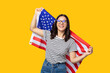 © Andrei - young cheerful multi ethnicity female holding american flag against yellow background