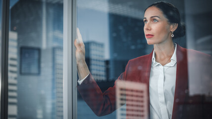portrait of stylish businesswoman looking out of window on a city. successful female ceo brainstormi