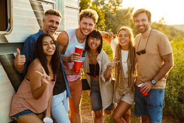 Wall Mural - Multiracial friends drinking beverages during picnic by trailer