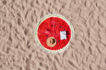 Canvas Print - Towel with book and straw hat on sandy beach, aerial top view